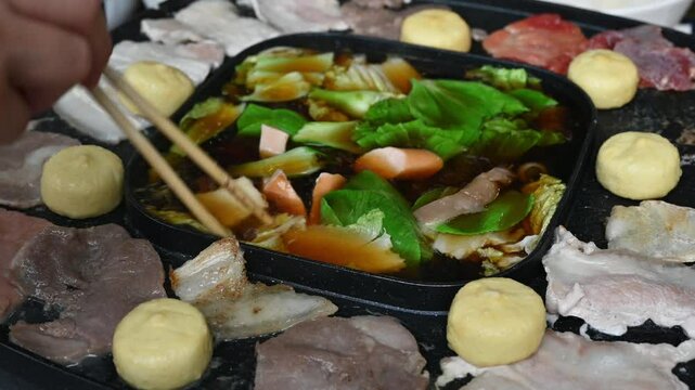 Footage of people enjoying their party with Korean BBQ and Shabu Shabu dinner. Korean BBQ is the popular method of grilling meat right at the dining table.