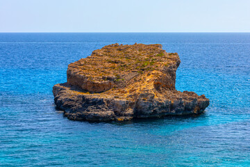 Obraz premium Small islet sits on the blue sea. Island in Blue Lagoon near Comino in Malta. Nature beauty and serenity