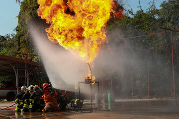 Firefighters and crates practice extinguishing fires with dangerous flames by using water to...