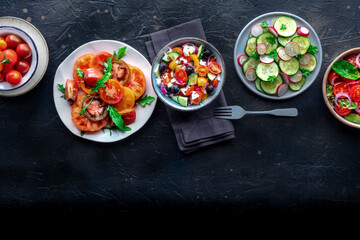 Fresh salads, overhead flat lay shot of an assortment. Variety of plates and bowls with green vegetables. Healthy food, with a place for text