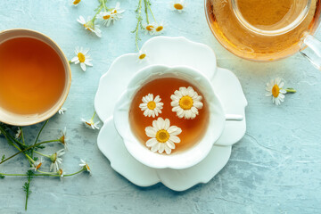 Chamomile flower tea. A tea cup and a tea pot with fresh medicinal flowers, natural organic remedy, overhead flat lay shot