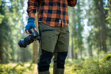 close up of hand holding professional camera in forest. nature photography concept.