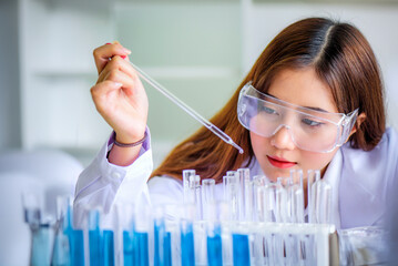 Attractive young Asian scientist woman lab technician assistant analyzing sample in test tube at...