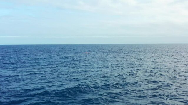 Drone flying view low angle over ocean and outrigger canoe alone rowing on blue sea in Hawaii. Sport activity on open sea. Hawaiian outrigger paddling and canoes