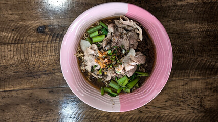 Boat noodles in a pink bowl on a wooden table