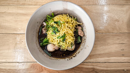 Boat noodles in a pink bowl on a wooden table
