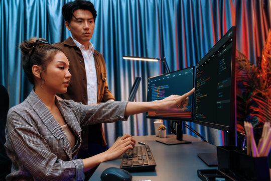 IT developers discussing with point to intelligent website development coder system running data online two screens information technology at neon light room at modern office. Infobahn.