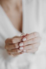 A woman is holding a ring in her hand. The woman is wearing a white robe