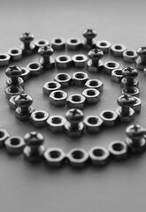Grayscale Image Of Mechanical Pattern Part Made With Same Metal Nuts And Screwed Cross Head Bolts. Vertical Stock Photo For Mechanism Illustration 