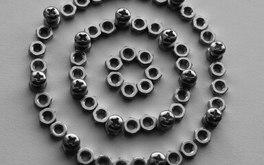 Pattern of perfect rings made of nuts with bolts screwed into them monochrome stock photo for...