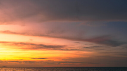 Sunset sky clouds over sea in the evening with orange, yellow gold sunlight in golden hour and dramatic fluffy, Horizon sea sky landscape, dusk sky background 