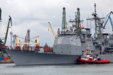 Tug boat supports military ship to dock in port