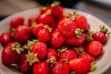 A close-up of fresh, ripe strawberries piled in a bowl, showcasing their vibrant red color and green leaves.