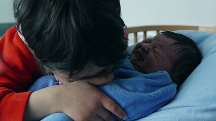 Tender moment between a young boy and his newborn sibling, captured as the boy kisses the baby, dressed in blue, showcasing love, family bond, and the arrival of a new family member