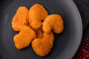 Delicious fresh crispy chicken nuggets on a dark concrete background