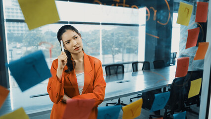 Professional young beautiful businesswoman thinking while standing at glass board with colorful...