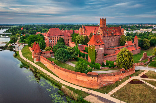 Castle of theTeutonic Order in Malbork by the Nogat river at sunset.
