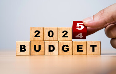 Hand flipping wooden block cube for change 2024 to 2025 Budget for money planning and allocation...