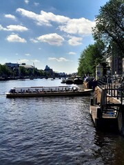 Tour boat turning into canal from the Amstel river in Amsterdam with flower arrangement in the foreground, on a clear sunny day in Amsterdam.