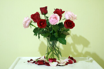 Bouquet of red and pink roses in vase. Fresh flowers in a transparent vase on the white table.