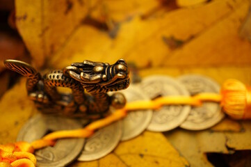 A figurine of a Chinese dragon on the background of autumn leaves. Horoscope and astrological forecast. Symbol of the year.