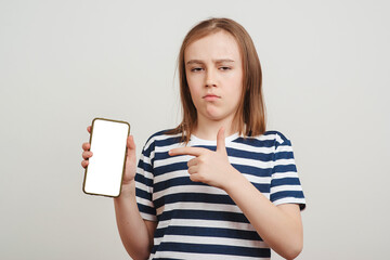 Serious boy holding mobile phone with white blank screen in hand. Gadget with empty free space for mock up.