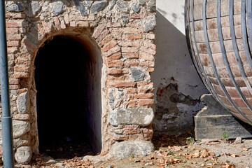 Fototapeta premium entrance to a decommissioned wine cellar with an old barrel next to it