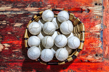 A basket filled with Basque pelota balls on a rustic wooden surface.