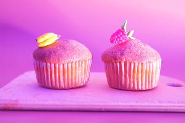 Sweet muffin decorated with raspberries and banana on a colored background.
