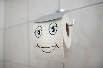 Kind and joyful toilet paper. A roll of toilet paper in a holder on the wall.