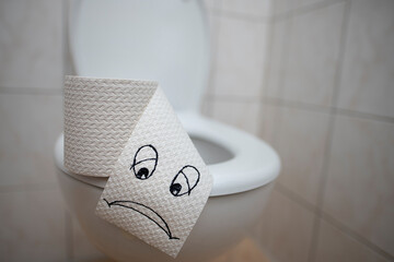 Toilet paper with a sad smiley face on the toilet.