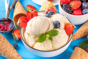 White ice cream bowl with vanilla gelato and fresh berries. Big portion of classic vanilla taste ice cream, with strawberry, raspberry, blueberry, blackberry, and waffle ice cream cones