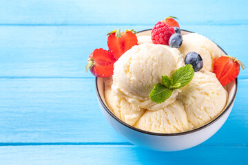 White ice cream bowl with vanilla gelato and fresh berries. Big portion of classic vanilla taste ice cream, with strawberry, raspberry, blueberry, blackberry, and waffle ice cream cones