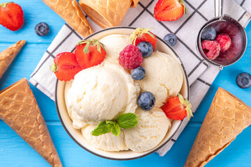 White ice cream bowl with vanilla gelato and fresh berries. Big portion of classic vanilla taste ice cream, with strawberry, raspberry, blueberry, blackberry, and waffle ice cream cones