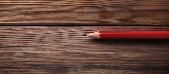 Obraz premium A red sharpened pencil, crafted with a folding knife, stands on a wooden background, providing a clear copy space image.
