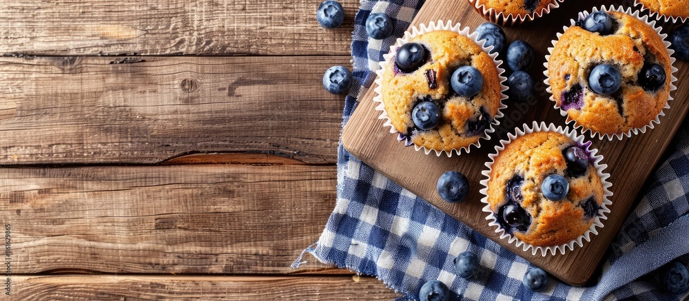 Poster blueberry muffins on a wooden board on a table with copy space image.