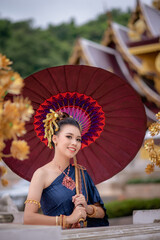 Woman wearing Thai dress visits beautiful temple in Thailand.
