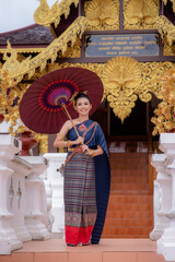 Fototapeta premium Woman wearing Thai dress visits beautiful temple in Thailand.