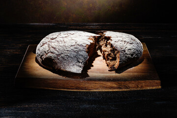 Two halved pieces of black rye round bread on a wooden surface. Selective focus