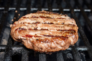 Homemade burger patty on a gas grill.  Ready to eat.