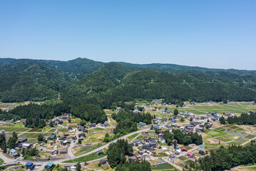 ドローン画像：青空と、緑に囲まれた田舎町