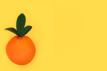 Orange citrus fruit healthy summer food minimal design with leaves on yellow background. High in bio flavonoids, antioxidants, vitamin c for immune system boost.