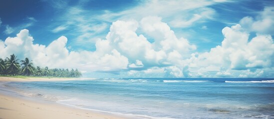 Obraz premium A serene tropical beach scene with a vivid blue sky, fluffy white clouds, and a textured background. Perfect for a summer vacation or travel-related design project, featuring a vintage color scheme