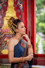 Woman wearing Thai dress visits beautiful temple in Thailand.