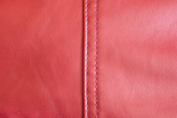 Fototapeta premium A close-up view of a red leather, highlighting its rich texture and the meticulous stitch work that runs down its spine and a vibrant red hue exudes luxury and the fine grain details. Clothes texture