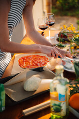 Prepping pizza mozzarella for cooking. Female chef. Outdoor Dining table of Homemade Pizza, Fresh Ingredients and red wine. Italian dream countryside romantic dinner 