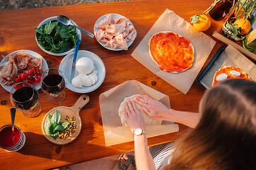 Making pizza dough. Female chef. Outdoor Dining table of Homemade Pizza, Fresh Ingredients and wine. Italian dream countryside romantic dinner 