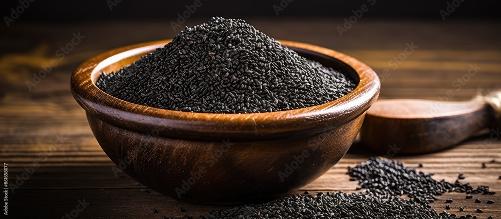 Poster black sesame seeds spice arranged in a pile on a black wooden surface with an available area for add