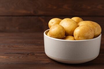 Young potatoes. Fresh potatoes  on a wooden background.Harvesting collection. organic, freshly dug potatoes. Agricultural background. Vegan. Vegetables.Place for text.Copy space