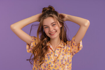 Fototapeta premium Portrait of a cheerful young girl in a floral shirt, touching her hair, set against a vibrant purple background, perfect for lifestyle and fashion content.